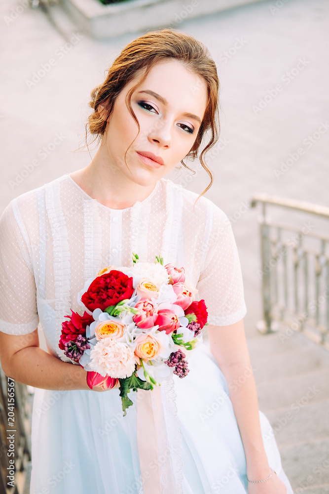 Adorable young bride with bridal bouquet standing on the staircase Adorable young bride with bridal bouquet standing on the staircase