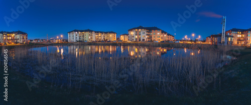Safe neighborhood with modern apartment buildings at midnight. Area is full of cars and lanterns. Reflection of buildings in the lake.  © Viesturs