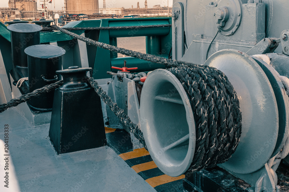 Closeup mooring equipment of ship. Mooring lines are fast on bollards, capstan and winch. Lines