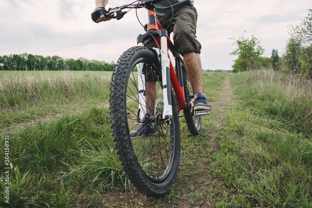 Cross-country riding, cycling, activity and sports. Man riding a bicycle at countryside road along a field