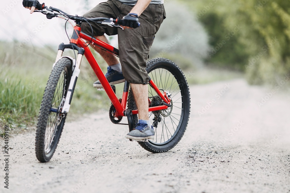 Young man riding a bicycle along dusty country road. Bicycle sports, traveling, healthy lifestyle and activity.