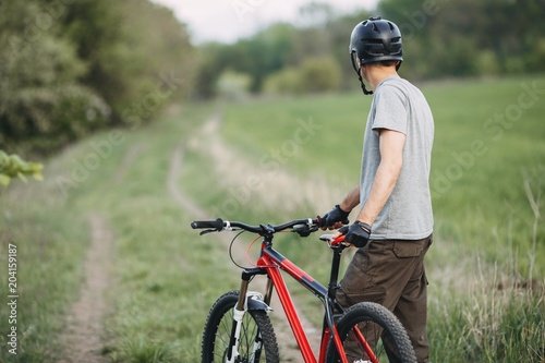 Young man in helmet traveling in the countryside riding a bicycle. Sports, leisure, healthy lifestyle and activity.