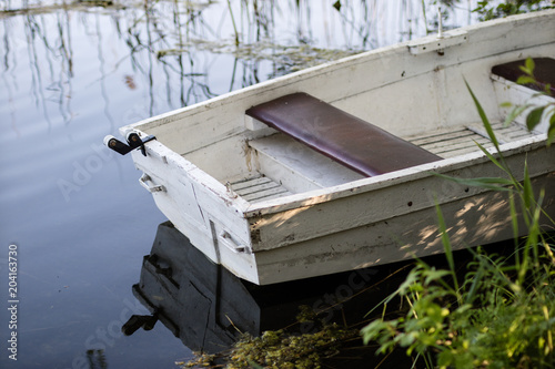 A fishing boat moored to the shore of the lake. Old fishermen's boat prepared for fishing on lakes. photo