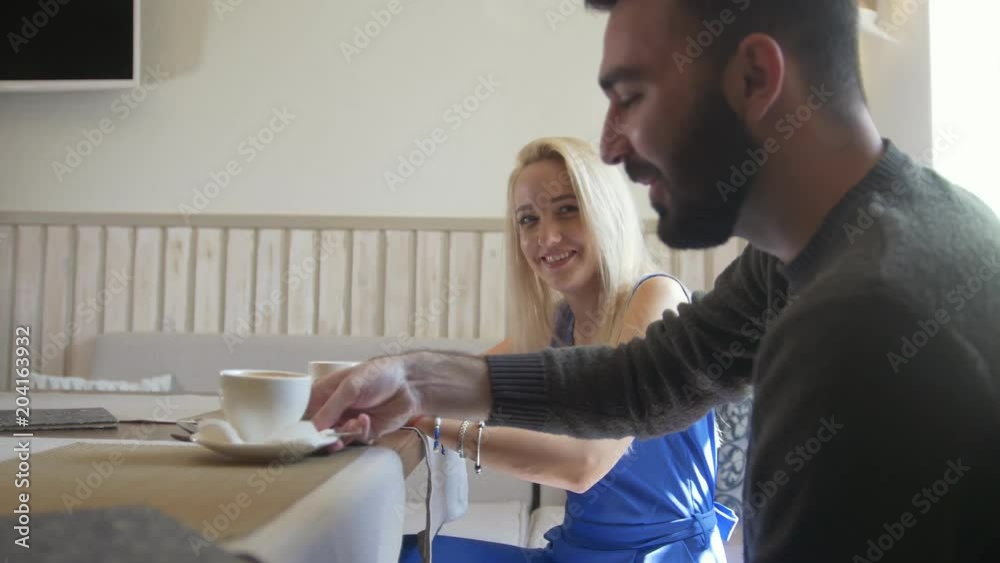 Young man and blonde woman takes the cups of coffee at the cafe Young man and blonde woman takes the cups of coffee at the cafe