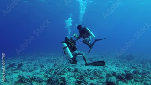Two scuba divers launch a signal buoy on the surface of the water, Indian Ocean, Fuvahmulah island, Maldives
