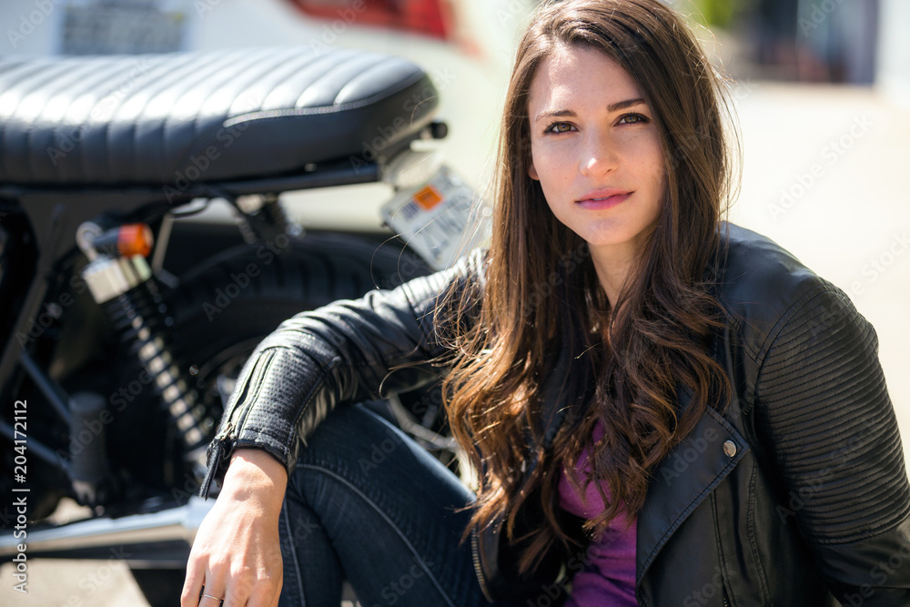 Beautiful sexy stylish biker chick in a leather jacket and blue jeans next  to a motorcycle Stock Photo | Adobe Stock