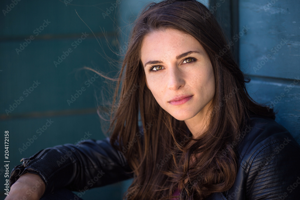 Dramatic serious headshot portrait of a tough edgy cool woman in a leather jacket Dramatic serious headshot portrait of a tough edgy cool woman in a leather jacket