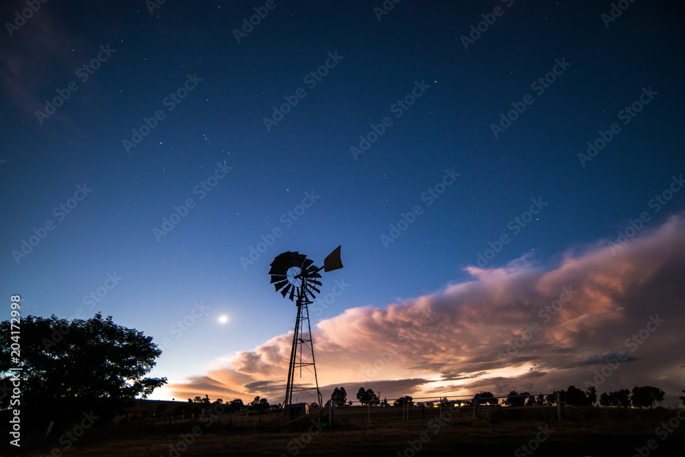 windmill silhouette with storm approaching at night windmill silhouette with storm approaching at night