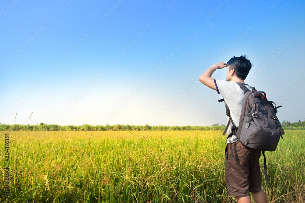 Asian Man backpacker standing and looking rice field with blue sky landscape
