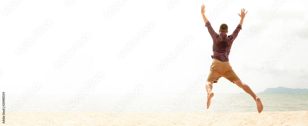 Obraz premium Energetic happy man jumping at the beach on summer holidays