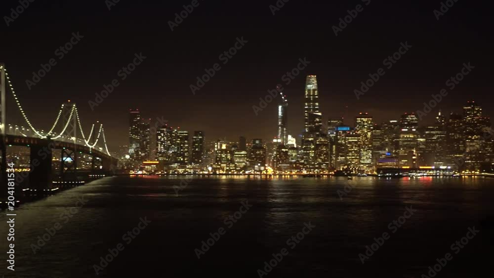 Slow pan of famous Bay Bridge of Silicon Valley, California that connects the Bay Area to San Francisco. City view at night.