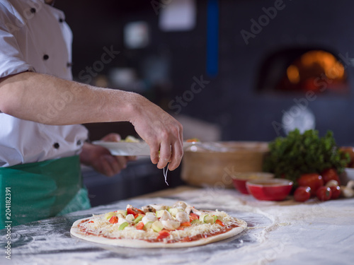 Fototapeta Naklejka Na Ścianę i Meble -  chef putting fresh vegetables on pizza dough