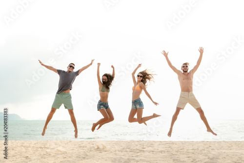 Happy energetic group of friends jumping at the beach during summer holidays