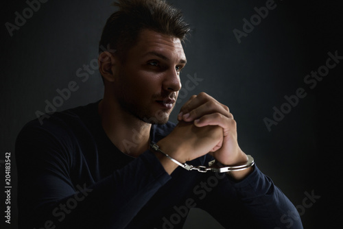 Suspect or criminal man with handcuffs in interrogation room after being caught