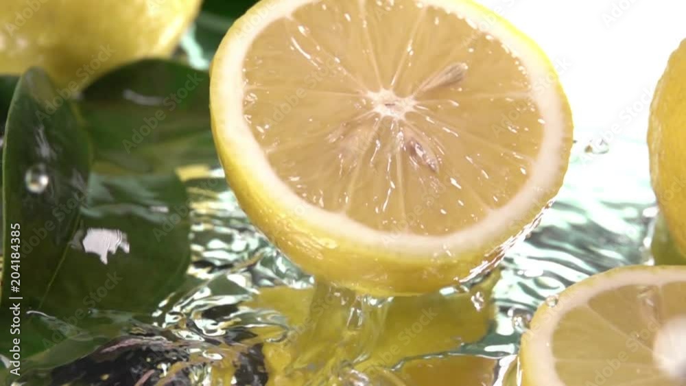Close up Lemon half slice hits on fresh water surface . Slow motion shot Close up Lemon half slice hits on fresh water surface . Slow motion shot