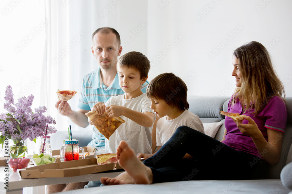 Beautiful young family with children, eating pizza at home and watching TV