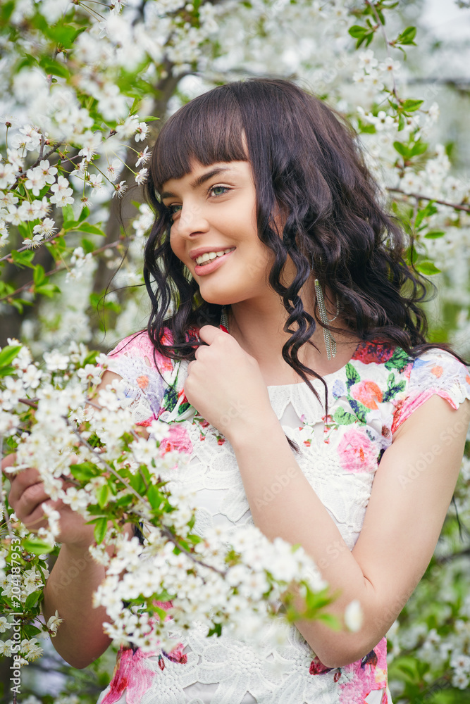 Young beautiful woman enjoying smell of blooming tree on a sunny day. Outdoor portrait in a blooming spring park Young beautiful woman enjoying smell of blooming tree on a sunny day. Outdoor portrait in a blooming spring park