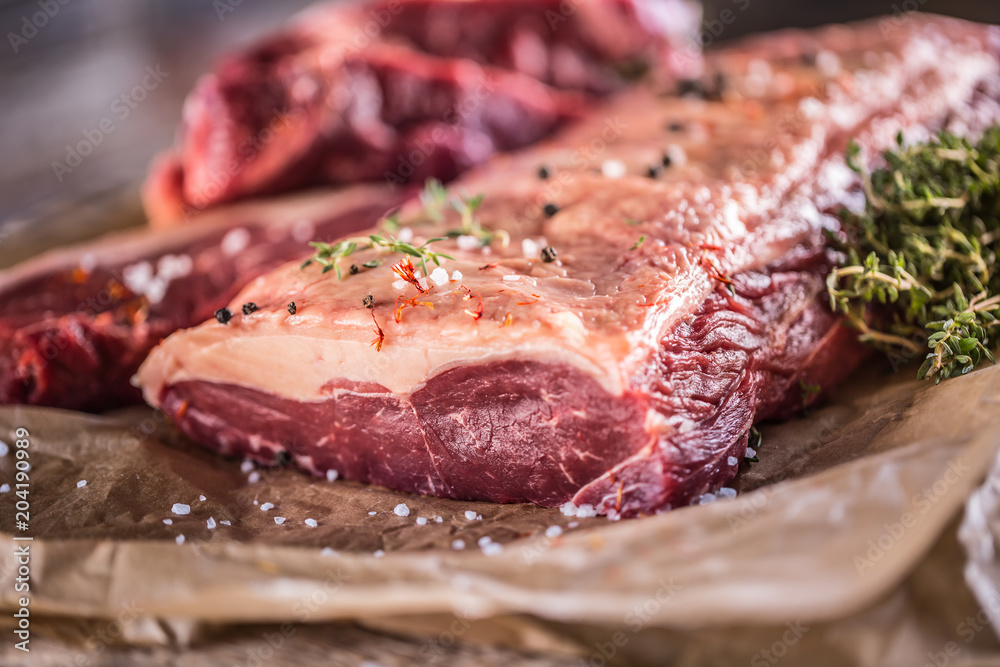 Raw rib eye beef steak with salt spices and herbs Raw rib eye beef steak with salt spices and herbs