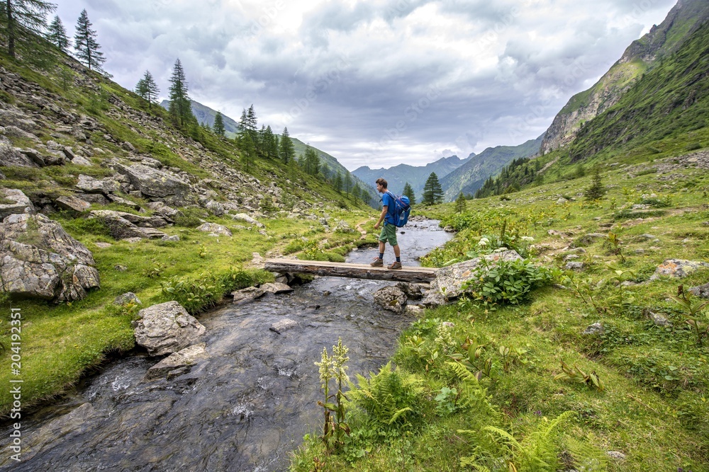 Hiker on a bridge over the Steinriesenbach, hiking trail to the Gollinghutte, Schladminger Hohenweg, Schladminger Tauern, Schladming, Styria, Austria, Europe Hiker on a bridge over the Steinriesenbach, hiking trail to the Gollinghutte, Schladminger Hohenweg, Schladminger Tauern, Schladming, Styria, Austria, Europe