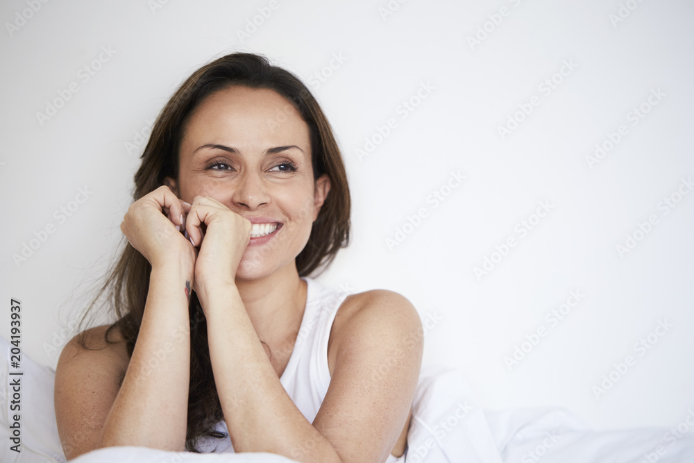 Beautiful woman smiling in bed, looking away Beautiful woman smiling in bed, looking away