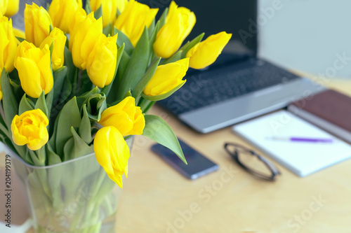 Fototapeta Naklejka Na Ścianę i Meble -  Large beautiful bouquet of yellow tulips on a desk in the office. Congratulations on the holiday or birthday. Flowers as a gift.