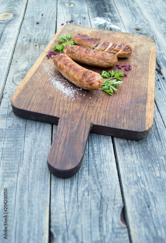 Grilled sausages with spices and herbs on wooden board