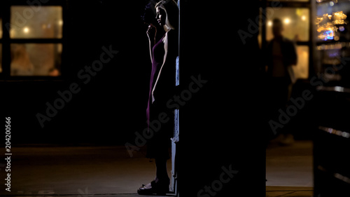 Lone attractive female smoking cigarette and thinking about life near nightclub