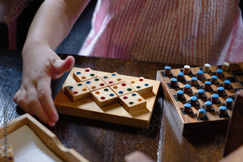 Tableau sur toile Child playing games, such as dominoes and othello on the old wooden table
