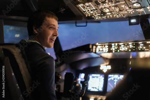 Young man piloting a plane in flight simulator for the training of the pilots photo