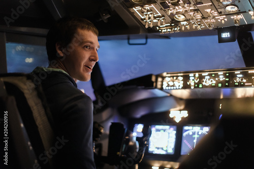 Tableau sur toile Young man piloting a plane in flight simulator for the training of the pilots