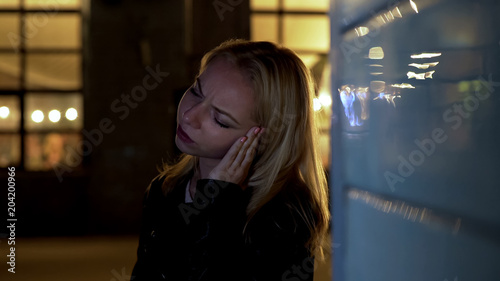 Photos Troubled woman standing near night club and suffering from headache, drunk lady