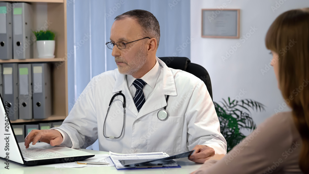 Doctor checking analysis on laptop, holding x-ray, digital devices replace paper Doctor checking analysis on laptop, holding x-ray, digital devices replace paper