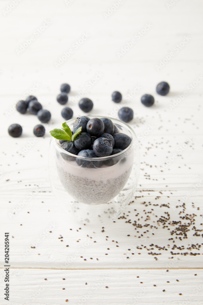 close up view of sweet chia seed pudding with blueberries and mint on white wooden surface close up view of sweet chia seed pudding with blueberries and mint on white wooden surface