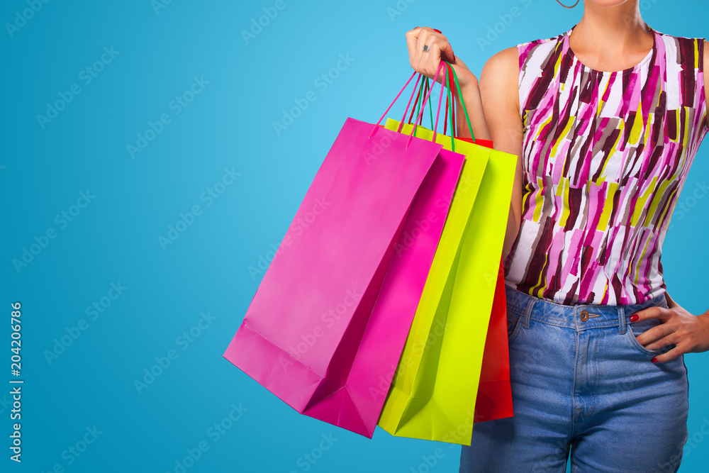 Shopping woman holding color bags isolated on blue background in black friday holiday. Summer shopping sale concept.