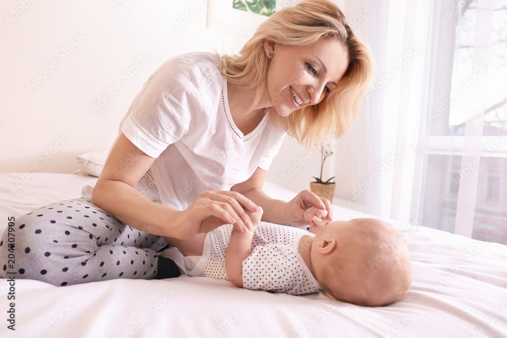 Young mother and her baby on bed at home Young mother and her baby on bed at home