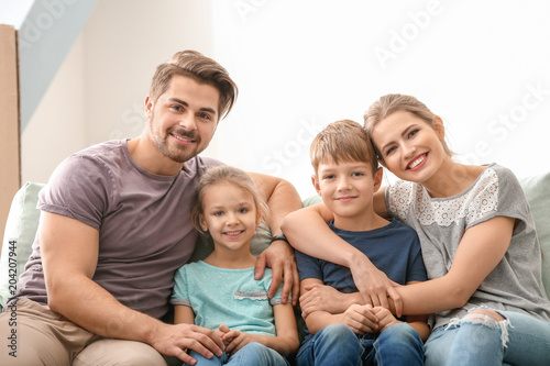 Portrait of couple with children on sofa at home. Happy family