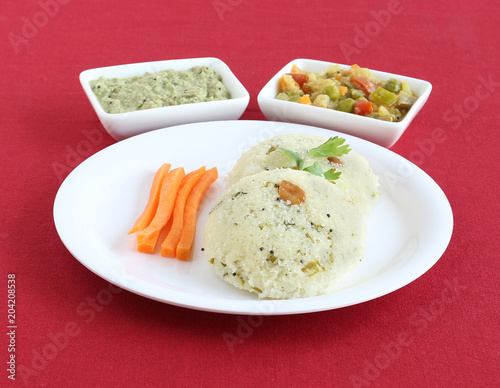 Rava idli, or semolina cake, south Indian traditional, popular and vegetarian breakfast with coconut chutney and vegetable curry as side dishes.