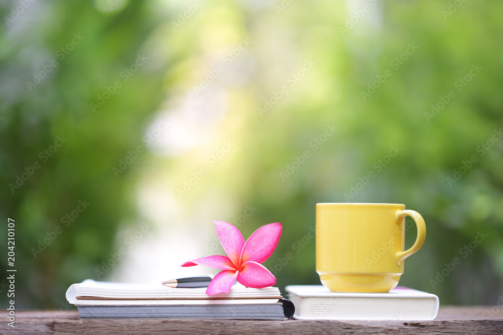 Yellow cup with plumaria flower and notebooks Yellow cup with plumaria flower and notebooks