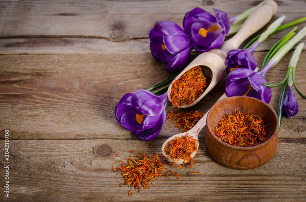 crocus flowers and spoon with soffron  on wooden table