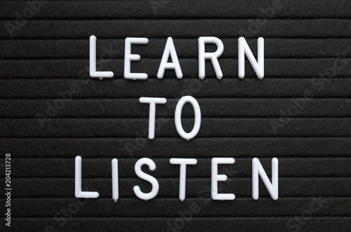 The words Learn To Listen in white plastic letters on a black letter board as a reminder for when dealing with people or improving your knowledge
