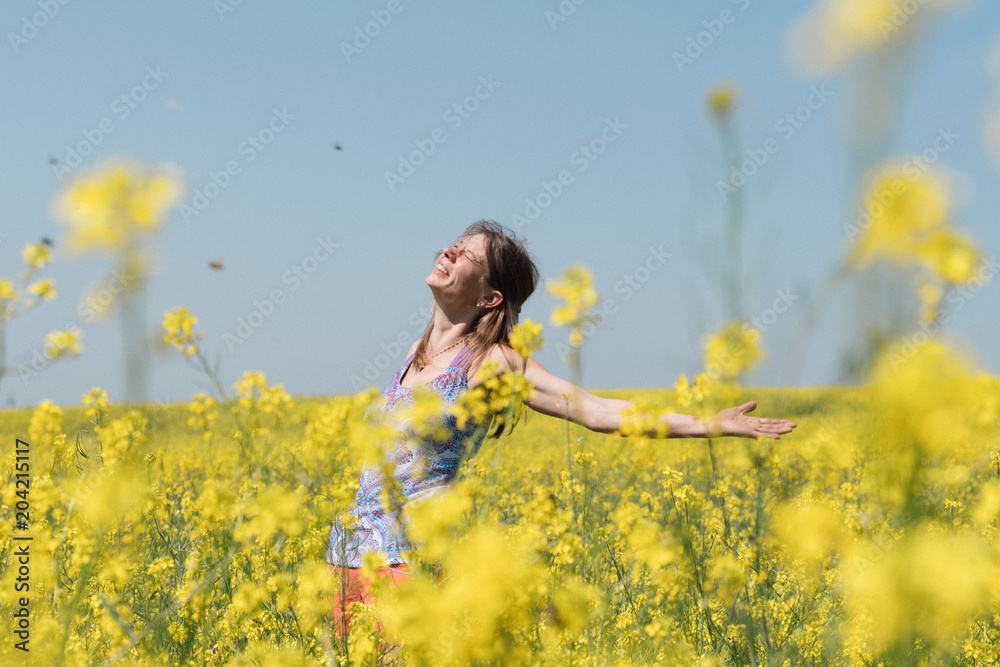 Smiling girl stands in the field of yellow flowers and look into the sky Smiling girl stands in the field of yellow flowers and look into the sky