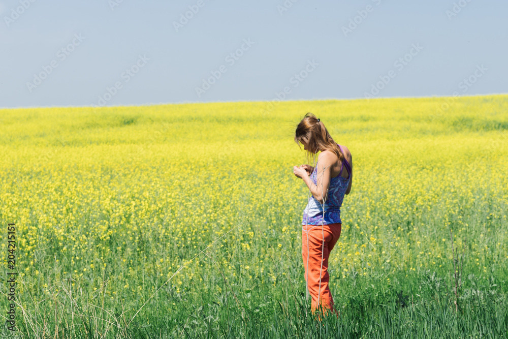 Smiling girl stands in the field of yellow flowers and look into the sky Smiling girl stands in the field of yellow flowers and look into the sky