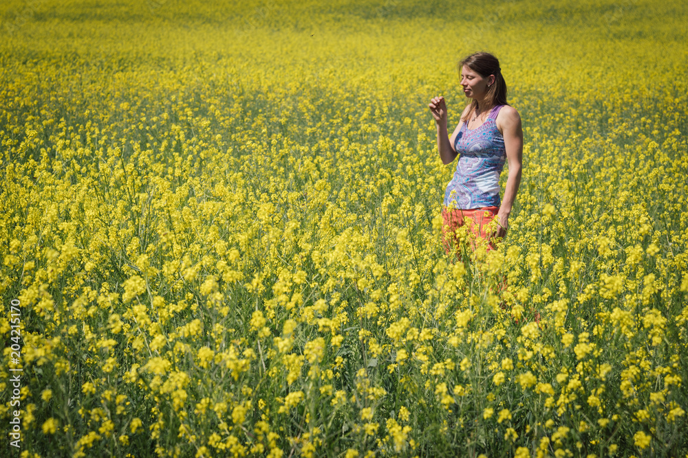Smiling girl stands in the field of yellow flowers and look into the sky Smiling girl stands in the field of yellow flowers and look into the sky