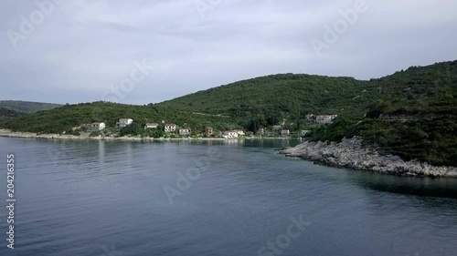 Aerial: Flying along coastline of beautiful Adriatic island Vis in Croatia. Green island with rocky shores and beautiful blue sea.