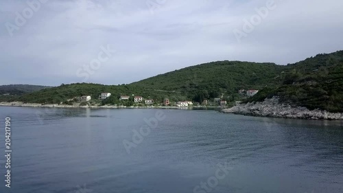 Aerial: Drone taking of at concrete pier on coast of island Vis in Croatia. Green island with rocky shores and beautiful blue sea.