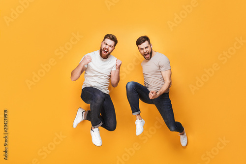 Two young cheerful men jumping together