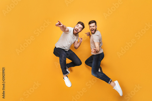 Two young happy men jumping together