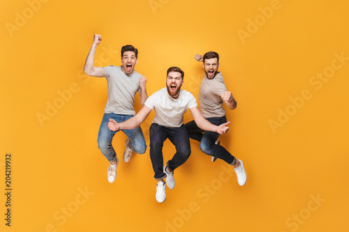 Three young happy men jumping together photo