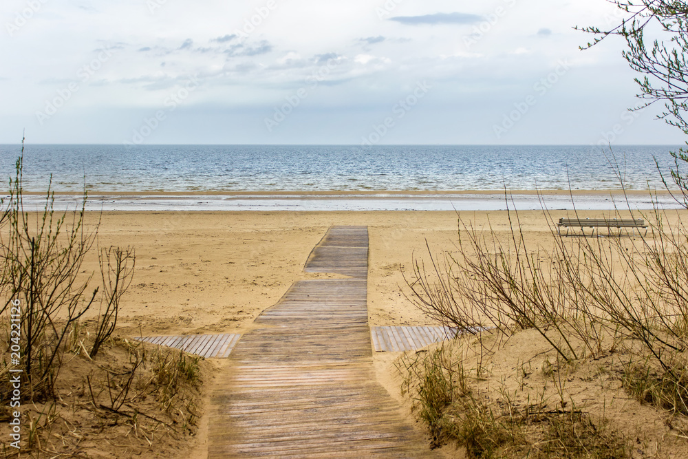 Wooden path leading to empty Baltic sea beach. Landscape with blue skies, sea and sand.