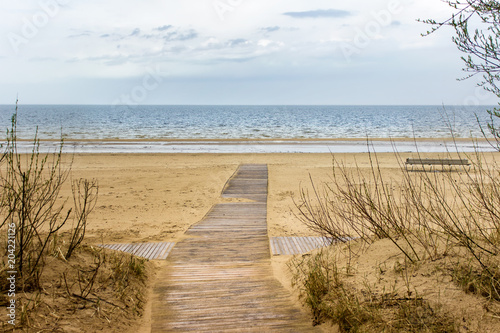 Wooden path leading to empty Baltic sea beach. Landscape with blue skies  sea and sand.